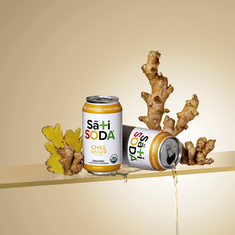 Two cans of Sä+hi Soda with ginger root on a beige background